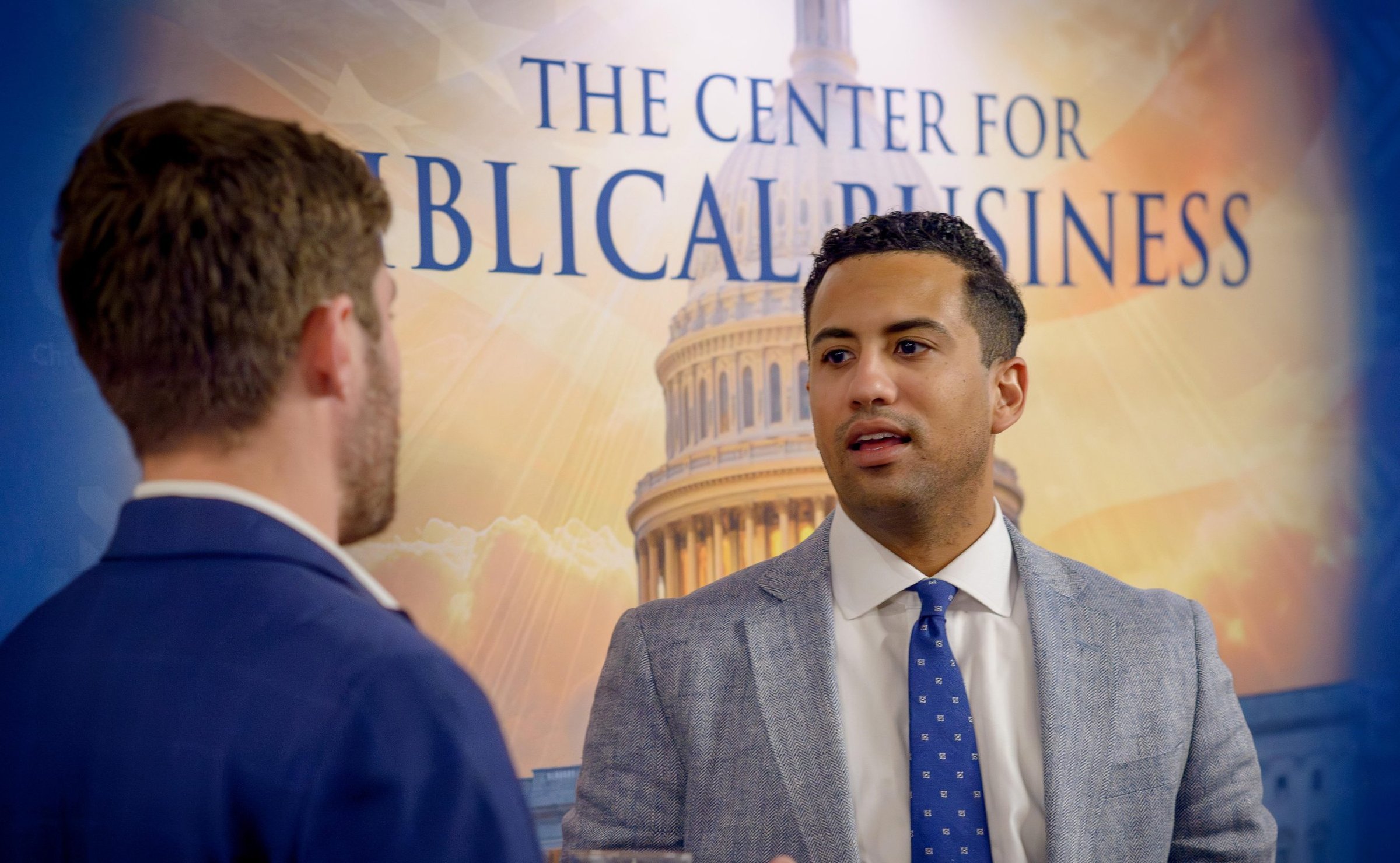 CEA attendees in conversation in front of the Center for Biblical Business backdrop